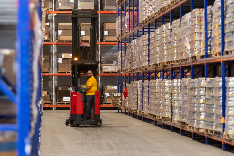 A man looking through pallets of products in a warehouse